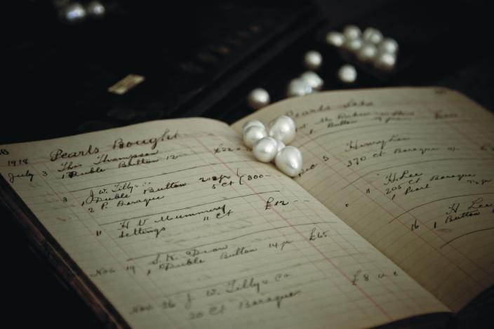 Image of pearls scattered on a business ledger. 